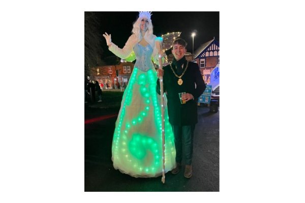 A photo showing the Deputy Mayor and a stilt walker at the Borrowash light switch on 2024